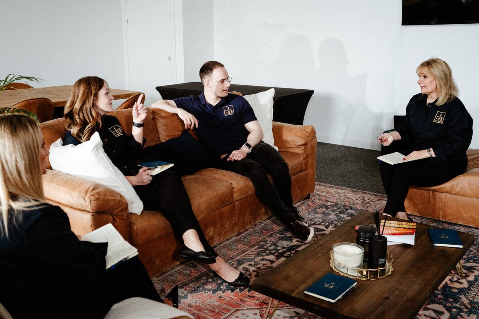 The Mindset HR team in discussion on lounge sofas, in branded shirts with notebooks in hand